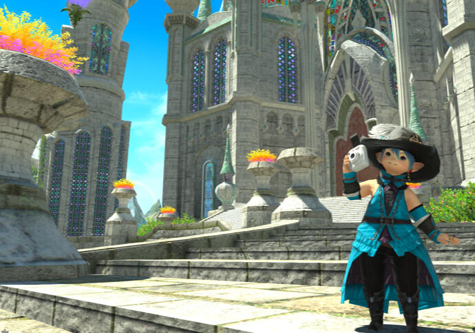 A smiling lalafell red mage in teal and black takes a photo in front of the castle